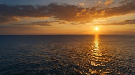 Golden sunset over calm ocean waters reflecting warm hues during early evening by the shoreline