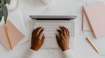 A person typing on laptop surrounded by stationery items, creating productive workspace atmosphere. elegant setup includes notebooks and pens, enhancing creative vibe