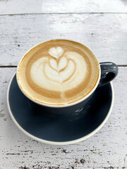 Close up shot of white coffee cup, hot cappuccino with heart-shaped latte art and flowers, food and drink concept.