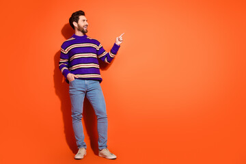 Full body photo of attractive young man point look empty space dressed stylish striped purple clothes isolated on orange color background