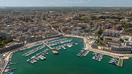 Obraz premium Aerial view of the historic center of Bisceglie, in Puglia, Italy. In the foreground is the tourist port, with many boats anchored, located on the Mediterranean Sea.