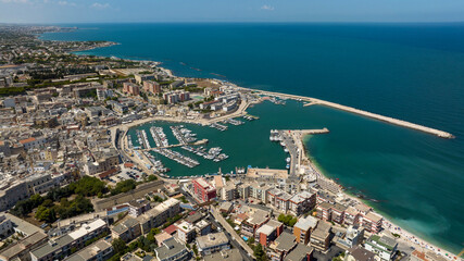 Aerial view of the historic center of Bisceglie, in Puglia, Italy. In the foreground is the tourist port, with many boats anchored, located on the Mediterranean Sea.