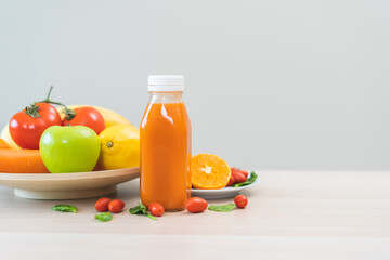 Orange, green detox juice in glass jars, bottle of vegetable fresh ingredients on table, carrot smoothie for diet, drinking healthy meal food for weight loss. Detox breakfast, isolated on background.