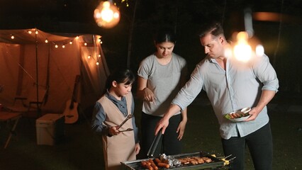 Family celebrate holiday in garden. Father, mother and child grill food for member. Outdoor camping activity to relax with meal and spend time with young generation cross generation gap. Divergence.