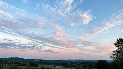 Fototapeta premium A pale pink and blue sky with wispy clouds on a warm summer morning, pink, soft focus