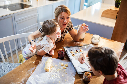 Mother baking cookies with children in bright kitchen