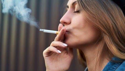 Fototapeta premium A smoker enjoying a cigarette; a close up view of a person smoking a cigarette and inhaling the smoke; selective focus; smoking cigarette; unhealthy and dangerous habit; smoke and tobacco; a smoker 