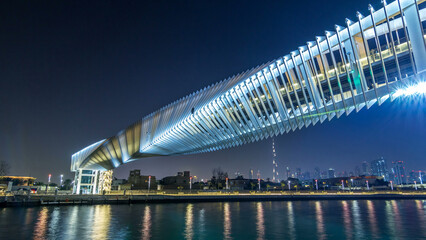 Fototapeta premium Futuristic Pedestrian Bridge over the Dubai Water Canal Illuminated at Night timelapse hyperlapse, UAE.