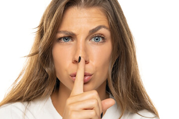 Naklejka premium Portrait of a serious young woman showing silence gesture.