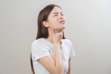 Sickness in inflaming asian young woman, girl use hand check self touch at sore throat, pain thyroid gland on neck or disease reflux, acid of suffer people on wall background. Medical and healthcare.