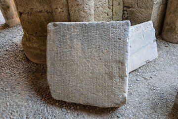 Archaeological Museum of Rhodes, Greece. Travel and history concept. Antique Greek text on stone tablets. Old cuneiform on a stones. Ancient inscription. Gray wall with historic letters.