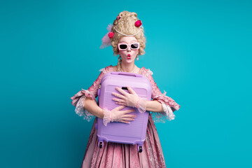 Photo of young impressed woman hold suitcase wear renaissance queen costume isolated on teal color background