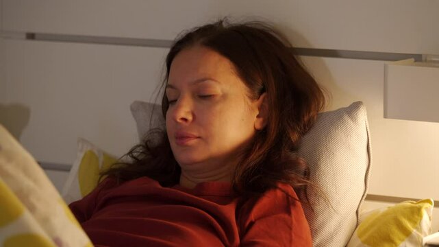 loving mother lying in bed with her little son in the bedroom at home, woman kissing child smiling