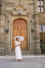 Woman Dress Umbrella Castle Entrance - A woman in a white dress holds an umbrella standing in front of the entrance to a castle.