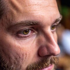 Fototapeta premium Extreme macro shot of a Caucasian male musician eye as he concentrates while playing Bavarian folk music at Oktoberfest. The focus is on the detailed texture of the eye, with the instrument he is play