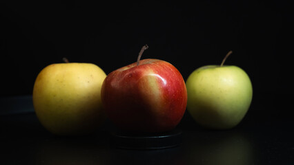 Three apples of different colors arranged on a dark background, emphasizing contrast and freshness.