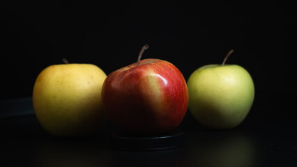 Three apples of different colors arranged on a dark background, emphasizing contrast and freshness.