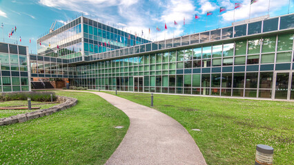 Modern low rise glass office building in business district and green lawn in inner yard timelapse...