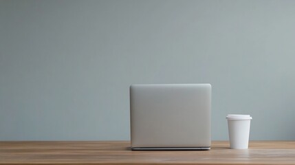 Obraz premium Minimalist Desk Setup with Laptop and Coffee Cup for Cozy Workspace