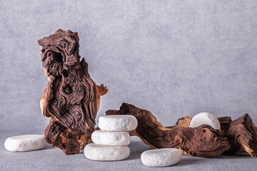 Empty stone podium, pieces of snag of Mopani tree on grey background. Minimalist eco backdrop. Round natural rocks and snags. Copy space, front view.