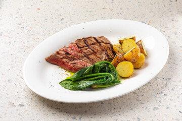 Portion of grilled top blade steak with potatoes and spinach