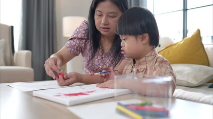 A special child with his mom paint and coloring together in the living room of the house