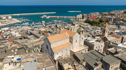 Aerial view of the Cathedral of Bisceglie, in Puglia, Italy. The Romanesque church of Saint Peter Apostle is located in the historic center of the town. In background is the port on Mediterranean Sea.