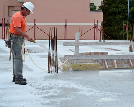 Construction carpenter waters the surface of a reinforced concrete floor slab on a construction site. concrete curing process