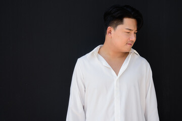 Obraz premium Portrait of Handsome Young Asian Man Against Black Background