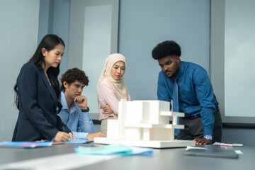 Fototapeta premium Focused group of professionals discussing an architectural model during a meeting, showcasing teamwork, planning, and creative problem-solving.