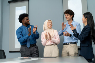 Smiling coworkers clapping and celebrating a colleague’s success in a professional office setting, showcasing teamwork and appreciation.