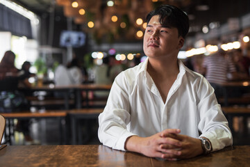 Portrait of Handsome Young Asian Man Sitting in Coffee Shop Restaurant