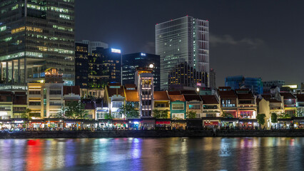 Fototapeta premium Singapore quay with tall skyscrapers in the central business district on Boat Quay night timelapse hyperlapse