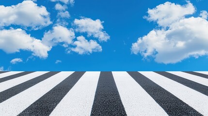 A clear view of a pedestrian crosswalk against a bright blue sky with fluffy white clouds, ideal for urban themes.