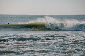 A surfer is riding a wave in the ocean. The water is choppy and the surfer is in the middle of a wave