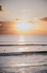 sunset on the beach and people swimming in the sea