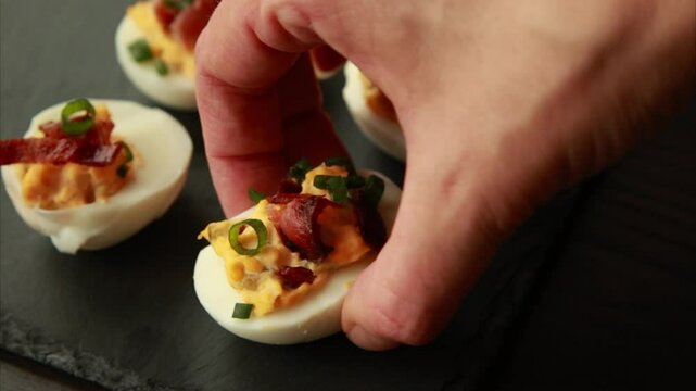  preparing delicious deviled eggs, topped with crispy bacon. A perfect party food idea 