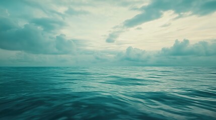 Fototapeta premium A serene view of the ocean with gentle waves and a cloudy sky at sunset.