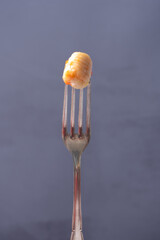 Fork with a gnocchi with tomato sauce.