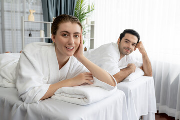 Obraz premium Caucasian couple customer enjoying relaxing anti-stress spa massage and pampering with beauty skin recreation leisure in day light ambient salon spa at luxury resort or hotel. Quiescent