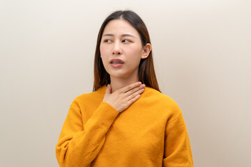 Fototapeta premium Sore throat in flu season. Young asian woman touching her neck and feeling pain in throat in the bedroom at home.