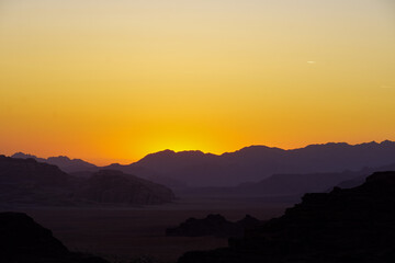 The beautiful sunset behind the mountains of Wadi Rum, a Unesco World Heritage Site in Jordan. Wadi Rum, also known as the Valley of the Moon, is a valley cut into sandstone and granite rocks.