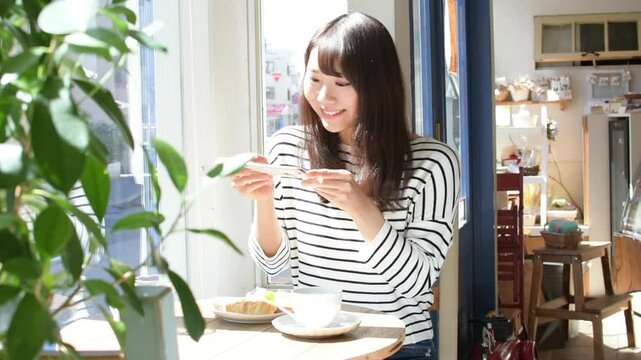 カフェでスマホを使って撮影をしている女性