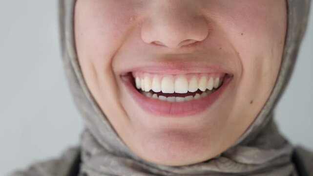 Cropped close up view lower part face of young islamic muslim woman, smiles in front of cam, revealing demonstrating teeth, advertising professional dental clinic services, whitening procedure