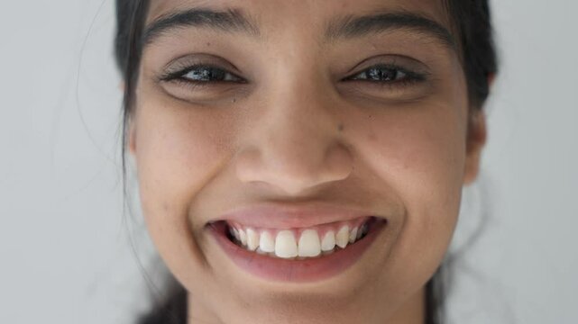 Extreme macro close up view part smiling attractive Indian ethnicity woman face, happy eyes looking at camera. Positive emotions, skin care anti aging treatment, eyesight surgery, lenses concept