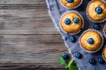 Fototapeta premium top view of muffins with blueberries on the wooden background with copy space