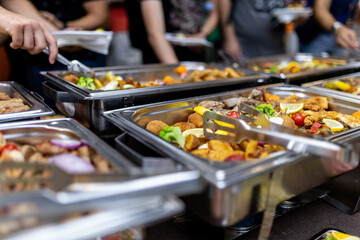 People enjoying a buffet meal with various dishes at a catered event indoors during the evening