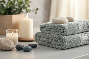 Spa setting with towels, candles, stones, and greenery