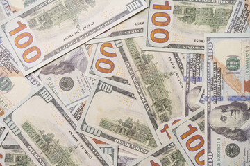 A US 100 dollar bill on top of a pile of scattered dollar bills, currency, texture and background.