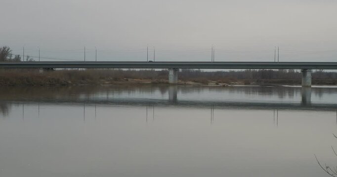 The structure. Rare cars drive over a large concrete bridge over the Talmenka River. Hand held. Siberia.